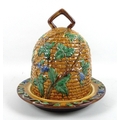A 20th century ceramic majolica cheese cover and stand, in the form of a beehive with moulded basket... 