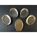 A group of five silver oval photograph frames, comprising a set of four frames, each 14cm oval, Char... 