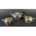 A George V three piece silver tea set, comprising of squat form teapot with ebonised handle and fini... 