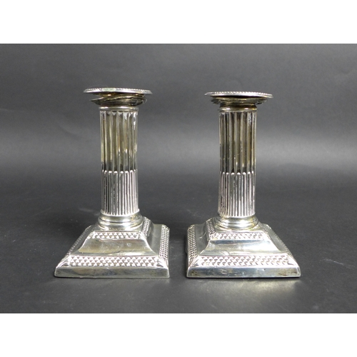 52 - A pair of late Victorian silver dwarf candlesticks, of Roman Doric column form, with square plinths,... 