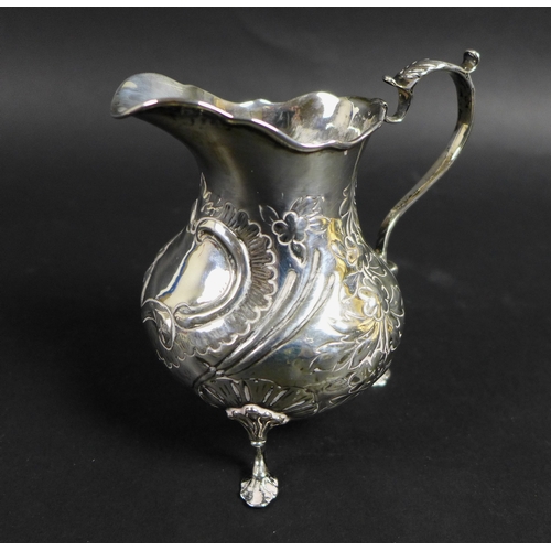 50 - A group of five silver items, comprising a Victorian milk jug with repousse decoration and C shaped ... 