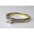 An 18ct gold and diamond ring with princess cut central stone, flanked by shoulders set with brillia... 