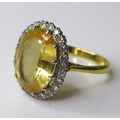 An 18ct gold and yellow topaz dress ring, the oval cut central stone of 12 by 8mm and surrounded by ... 