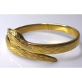 A 9ct gold snake form hinged bangle, with red stone eyes, 20.1g, 6.4cm internal width.