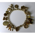 A 9ct gold charm bracelet with heart padlock clasp, with seventeen 9ct gold charms including a lante... 