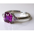 A platinum, ruby and diamond three stone ring, the central cushion cut pink ruby of approximately 1c... 