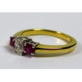 An 18ct gold, diamond and ruby three stone ring, the central oval cut diamond of 4.47 by 3.2mm and f... 