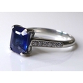 A platinum, sapphire and diamond ring, the emerald cut deep cornflower blue sapphire of approximatel... 