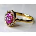 An 18ct rose gold, pink sapphire and diamond dress ring, the central oval cut deep rose pink stone o... 