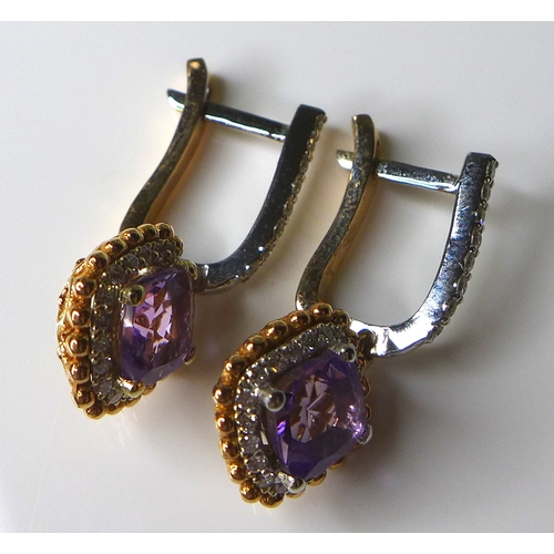 323 - A pair of 18ct white and rose gold, amethyst and diamond earrings, with central cushion cut amethyst... 