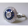 An 18ct white gold, diamond and sapphire ring, of Art Deco style circular design, the central brilli... 