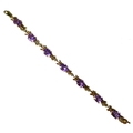 A 9ct gold and amethyst bracelet, formed of seven links each with an oval cut stone in four claw set... 