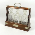 A Victorian oak tantalus, EPNS mounted, engraved shield to front, a single and a pair of cut glass d... 