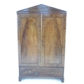 An early 19th century figured mahogany wardrobe, pointed cornice over two doors with brass edging, o... 