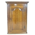 A George III mahogany corner cupboard, flat front single paneled door with brass H hinges, four fixe... 