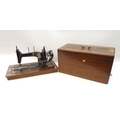 An early 20th century sewing machine with inlaid wooden case, hand powered, no maker's name.