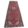 A Hamadan runner, with red ground and floral decoration, 300 by 106cm.