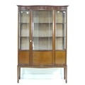 An Edwardian mahogany serpentine fronted display cabinet, line inlaid, bowed glass, three fabric lin... 