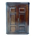 A George III oak corner cupboard, cornice over twin panelled doors enclosing two shaped shelves and ... 