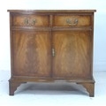 A reproduction mahogany veneered serpentine fronted cabinet, in the Regency style, with two drawers ... 