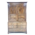 A George III oak dressing cupboard, with cornice over two panelled doors enclosing a hanging space, ... 
