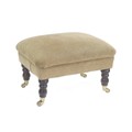 A modern upholstered footstool, overstuffed in gold coloured fabric, turned legs and brass castors, ... 