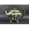 An Edward VII silver teapot, of Rococo bombe form, with ebonised finial and handle, raised on four f... 