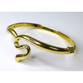 A 14ct gold bangle of sinuous design, with hinged clasp, 19.3g.