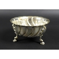 A late Victorian silver circular wrythen fluted sugar bowl, with piecrust rim, raised upon three she... 