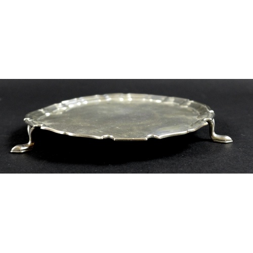 52 - A George V silver waiter tray, of circular form with Chippendale pie crust edge, raised on three fee... 