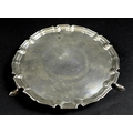 A George V silver waiter tray, of circular form with Chippendale pie crust edge, raised on three fee... 