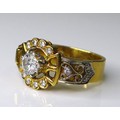 An 18ct gold and diamond ring of ornate buckle design, the central brilliant cut diamond of approxim... 