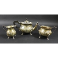 An Edward VII silver three piece tea set, of squat bodied form with scalloped rims, relief decorated... 