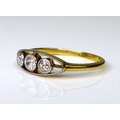 A 9ct gold three stone diamond ring, central brilliant cut diamond approximately 0.06ct, each of the... 