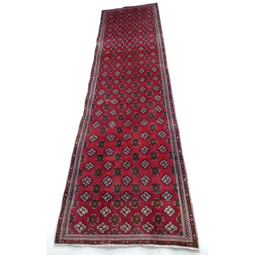 307 - A Turkman runner, with red ground and multiple guls to field, narrow borders, 295 by 83cm.