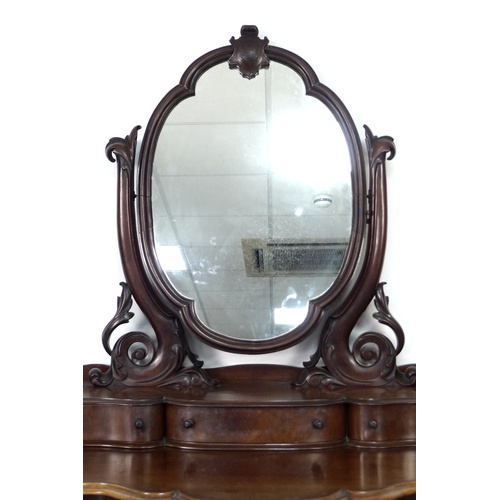 293 - A Victorian mahogany dressing table, with oval mirror on shaped supports, three trinket drawers, the... 