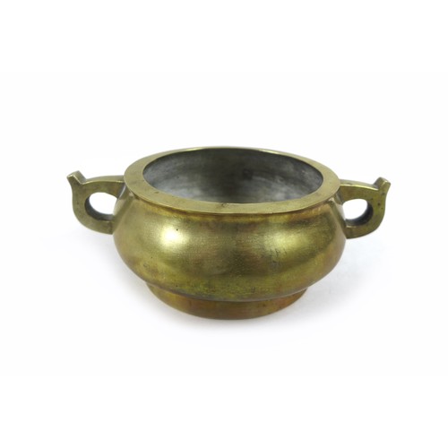 25 - A Chinese polished bronze censer, of twin handled squat circular form, raised on a high foot rim, ca... 
