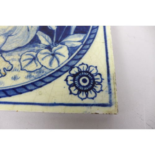 63 - A 19th century Mintons blue and white tile, featuring a cherub holding up a necklace, bearing marks ... 