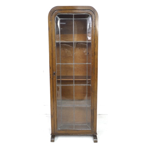 277 - An early 20th century oak bookcase, featuring an arched top, a single leaded glazed door, with curve... 