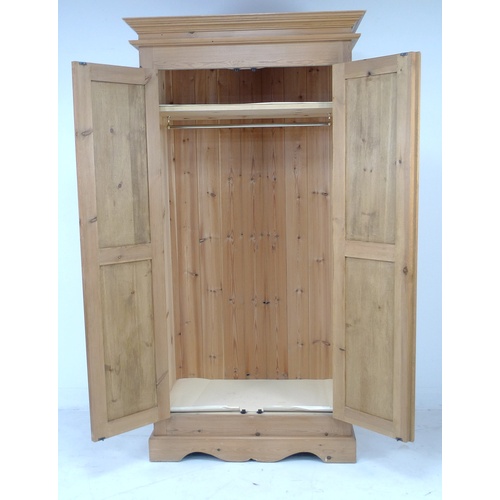 242 - A modern pine wardrobe, double doors opening to reveal a hanging space, 102.5 by 60 by 198cm high.