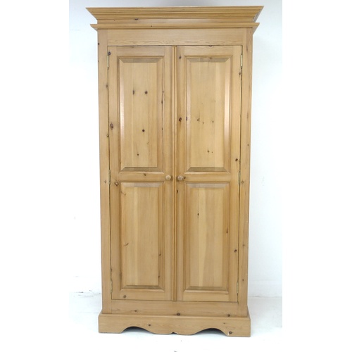 242 - A modern pine wardrobe, double doors opening to reveal a hanging space, 102.5 by 60 by 198cm high.