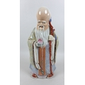A modern Chinese porcelain figure, modelled as Shou Lao, the god of longevity, standing holding a st... 