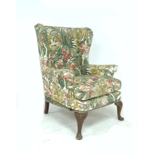 244 - A Parker Knoll wingback armchair, with foliate upholstery, raised upon cabriole legs with pad feet, ... 