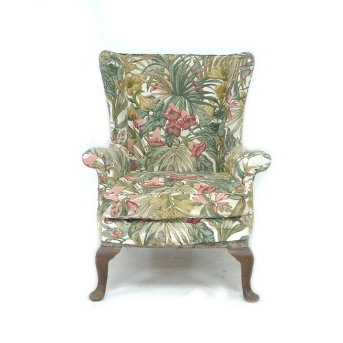 244 - A Parker Knoll wingback armchair, with foliate upholstery, raised upon cabriole legs with pad feet, ... 