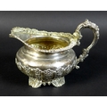 A George IV silver milk jug, with profuse repousse and applied decoration, raised on four shell and ... 