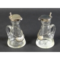 A pair of Edwardian clear glass and silver mounted noggin flasks, each of tapering form with mounted... 