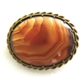 A 19th century fire banded agate brooch, of polished oval form, in an unmarked 14ct yellow gold milg... 