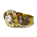 An 18ct gold and diamond ring of ornate buckle design, the central brilliant cut diamond of approxim... 