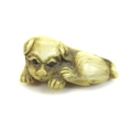 A Japanese ivory netsuke of a puppy, circa 1900, modelled in recumbent pose, unsigned, 5 by 3.5 by 2... 