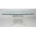 A modern design dining table, shaped rectangular clear glass surface with bevelled edge raised on tw... 